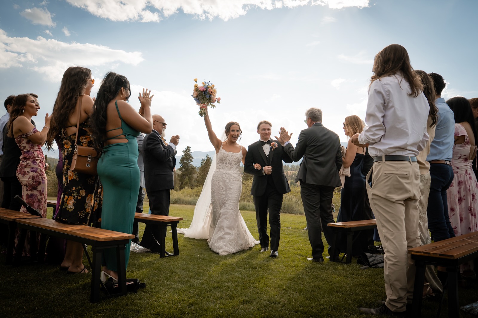 Bride and groom walking back up the aisle as guests cheer at a Colorado wedding