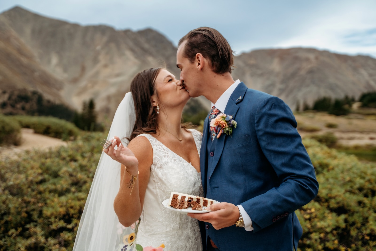 Newlyweds kissing in front of a Colorado mountain range after their ceremony