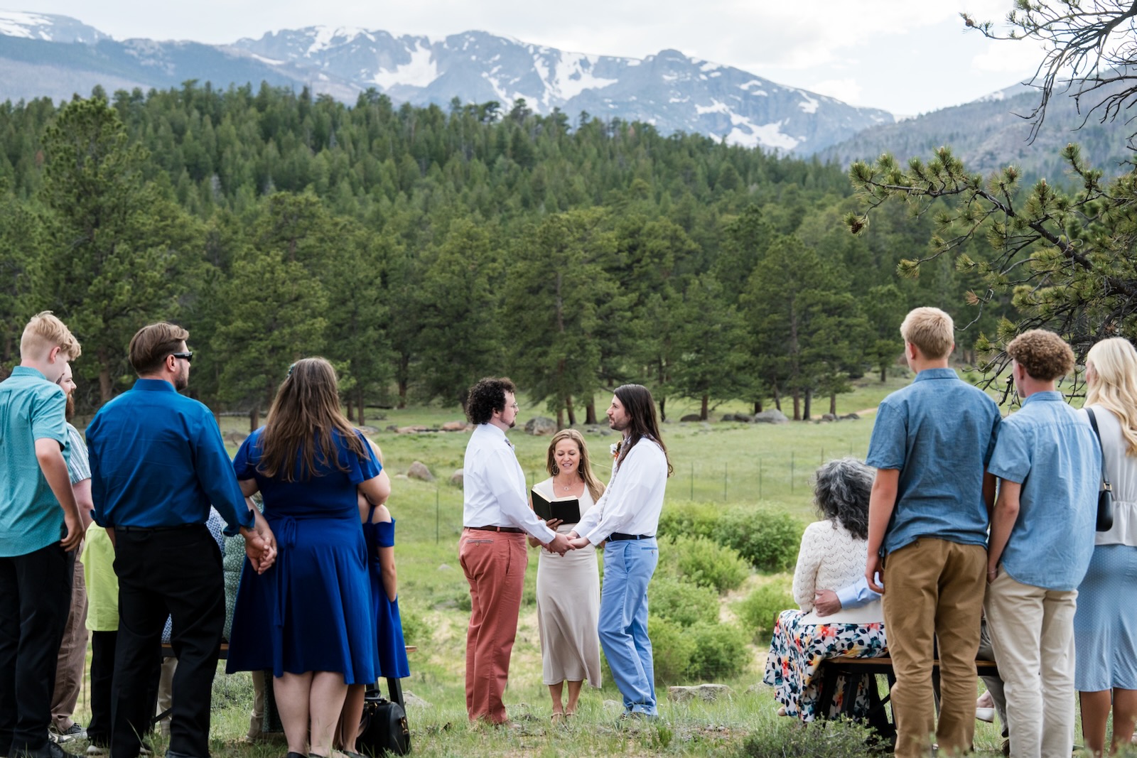 Colorado officiant leading a mountain meadow wedding ceremony with guests looking on